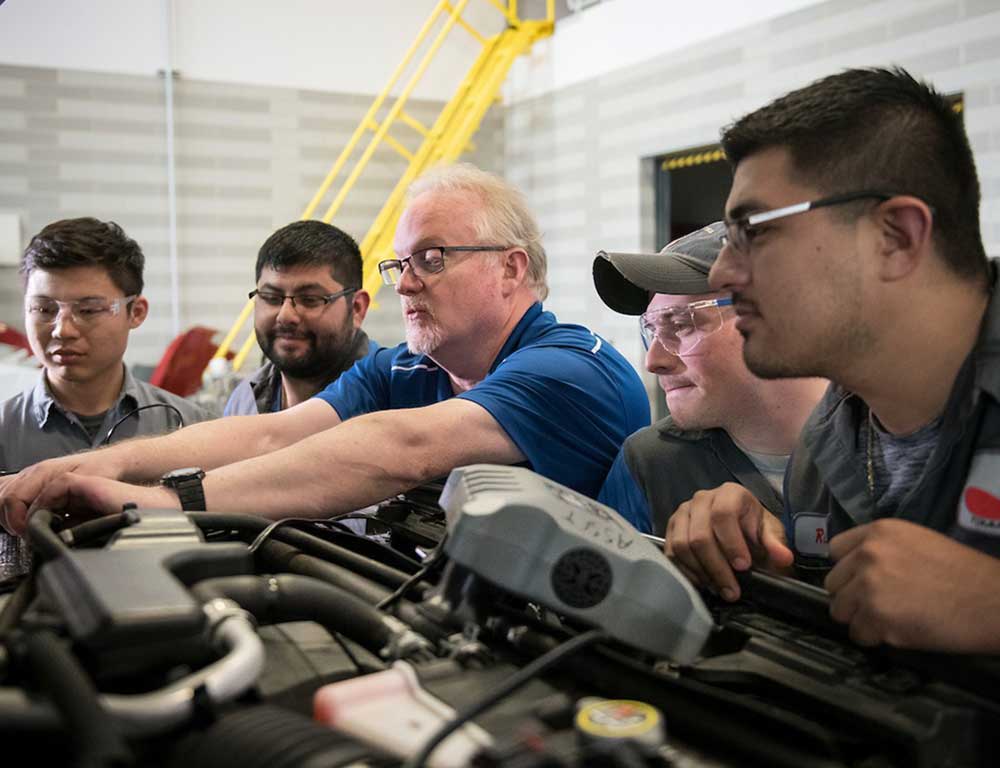 Automotive Technology students with instructor working on an engine