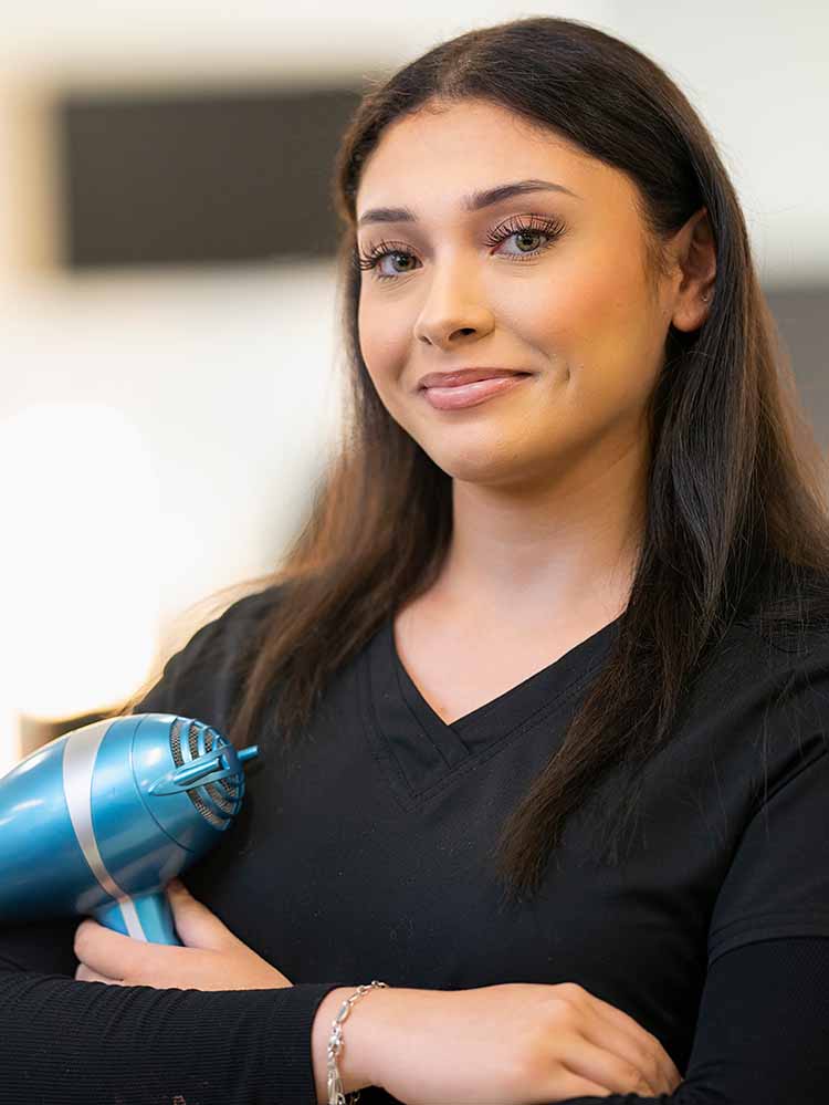 female cosmetology student holding hair dryer
