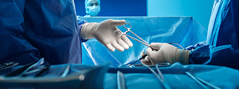 Surgical technologist handing tools to surgeon in operating room