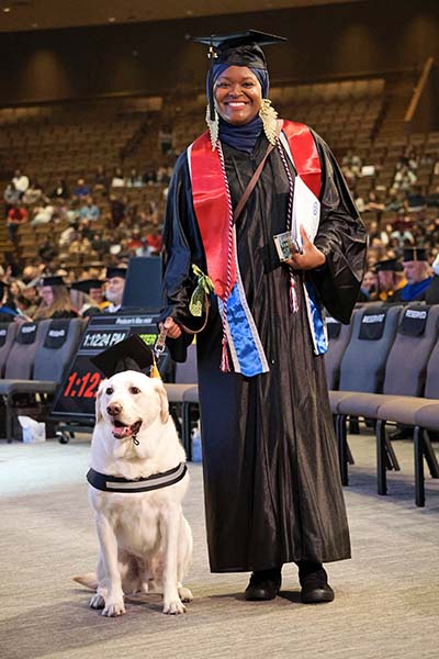 San Jacinto College graduate Tonie Marshall standing with her service dog Rocco at the commencement ceremony